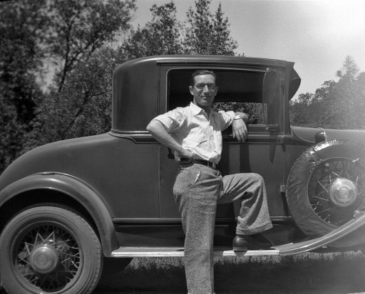 A man leaning against a car, giving us a casual pose.
