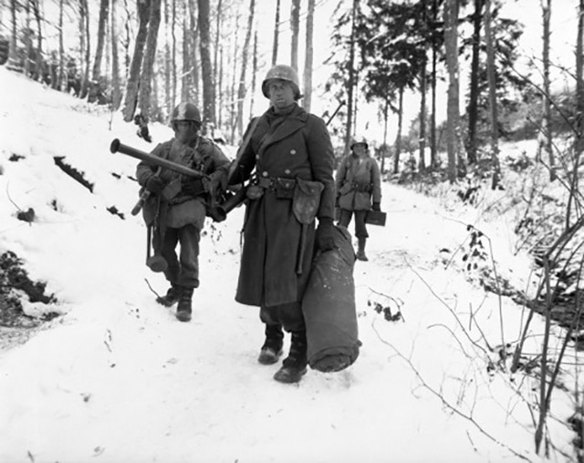 Soldiers trekking through snowy terrain during the Christmas 1944 military campaign.