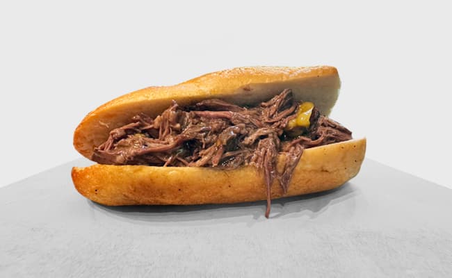 A 4-Ingredient Italian Shredded Beef sandwich with peppers in a toasted bun on a plain background, perfect for Lunchtime Meal Prep.