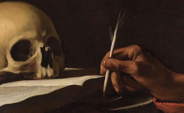 A human skull rests on a surface beside a hand holding a quill pen, poised to write on a piece of paper—an evocative scene for those who seek powerful quotes or thought-provoking quotes about death.