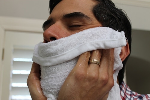 Homemade barbershop hot towel applying on face.