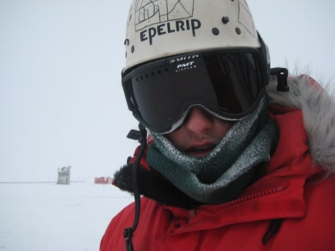 A Driller/Researcher wearing a helmet and goggles in the Antarctic snow.