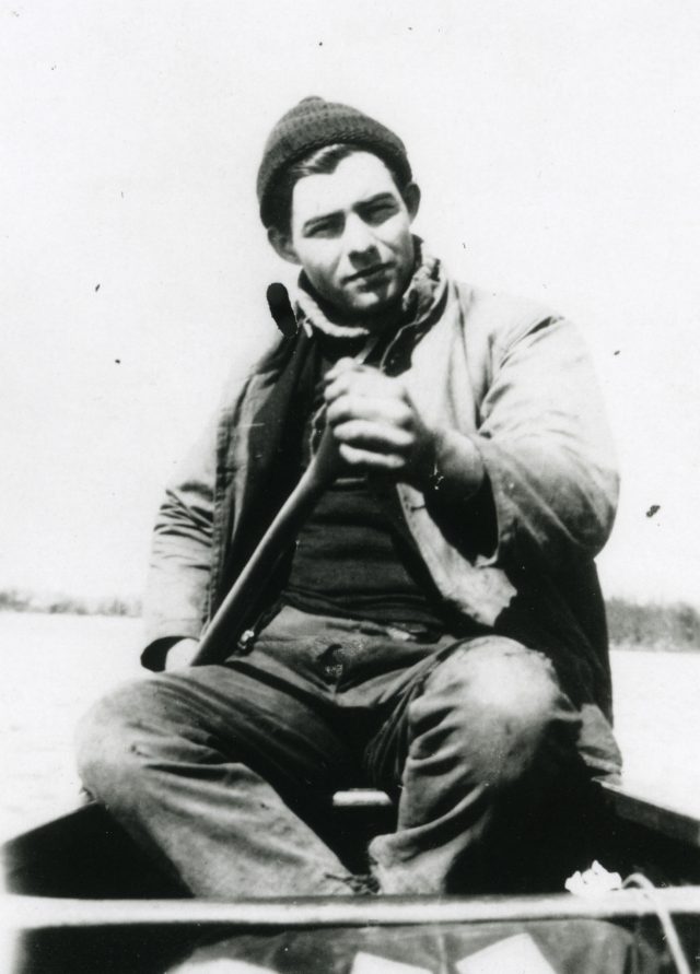 Ernest Hamingway sailing a boat with oar in hand.