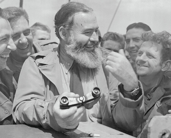 Hemingway holding Binocular and smiling with group.