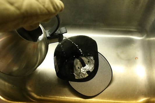 Pouring the hot water into baseball cap.