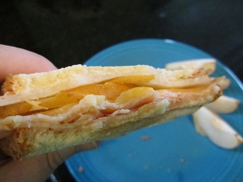 A person holding a turkey sandwich with Asian pears and pecans.