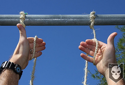 Man folding the two ropes in his hands.