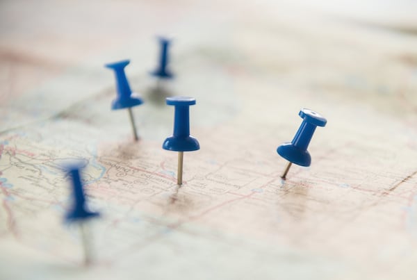 Blue pushpins decide locations on a map for where to live.