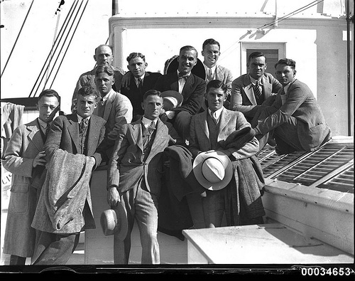 Vintage group of men friends in suits on boat.