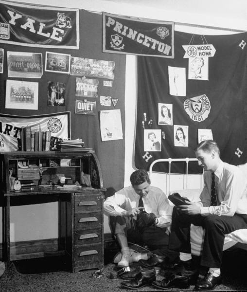 A group of men sitting in a room with a bed, protecting.