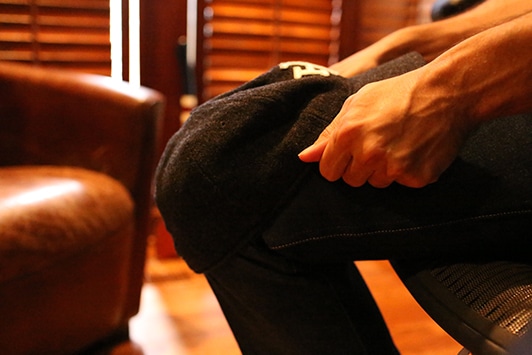Man folding a cap on legs.