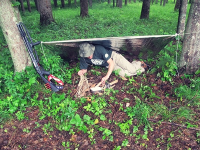 Creek stewart using emergency blanket in survival kit for shelter.