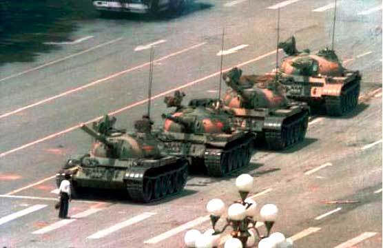 A group of developing tanks on a street in front of a man exhibiting manly courage.