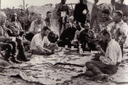 A group of cowboys sitting around a campfire in the jungle.